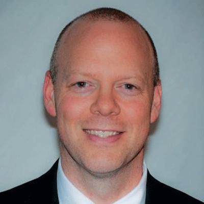 A man in a suit and tie is smiling for the camera.