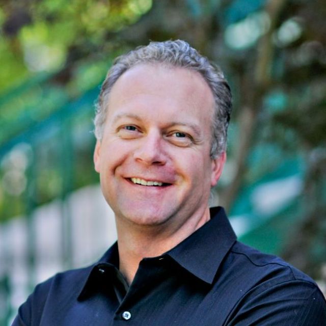 A man in a striped shirt is smiling for the camera