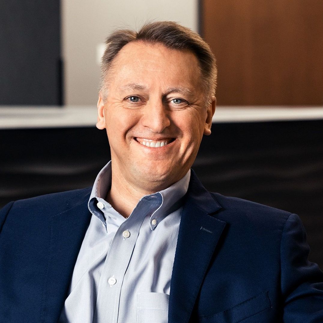 A man in a suit and striped shirt is smiling for the camera.