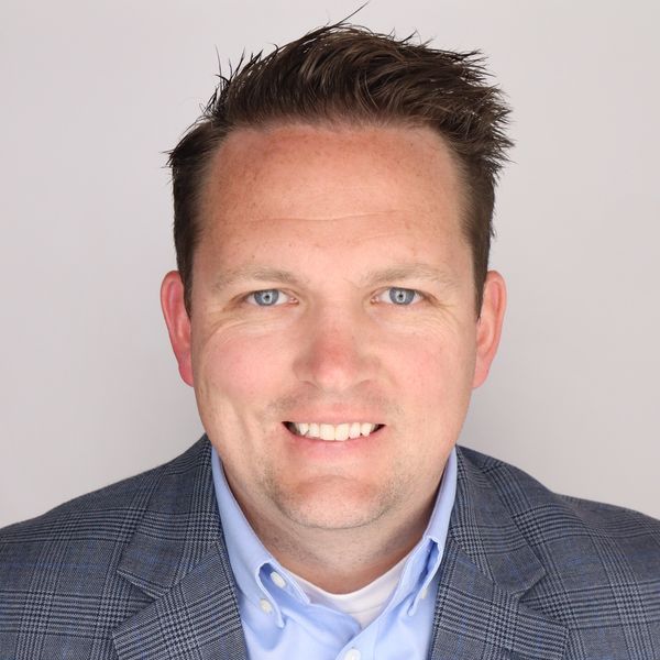 A man in a suit and tie is smiling for the camera