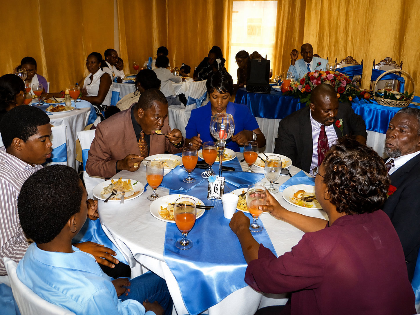 People seated at a banquet table with blue-and-white decor, eating and talking in a dining hall