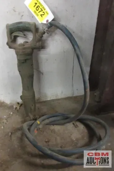 A hammer with a hose attached to it is sitting on a rock.