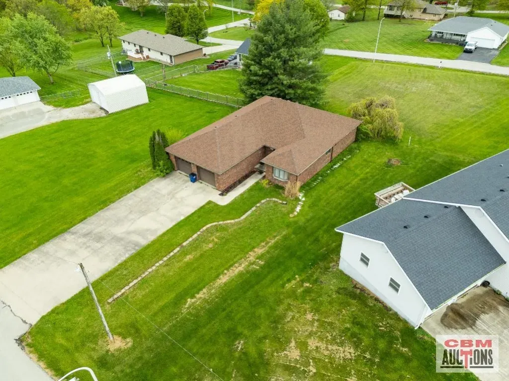 An aerial view of a house with a brown roof in a residential area.
