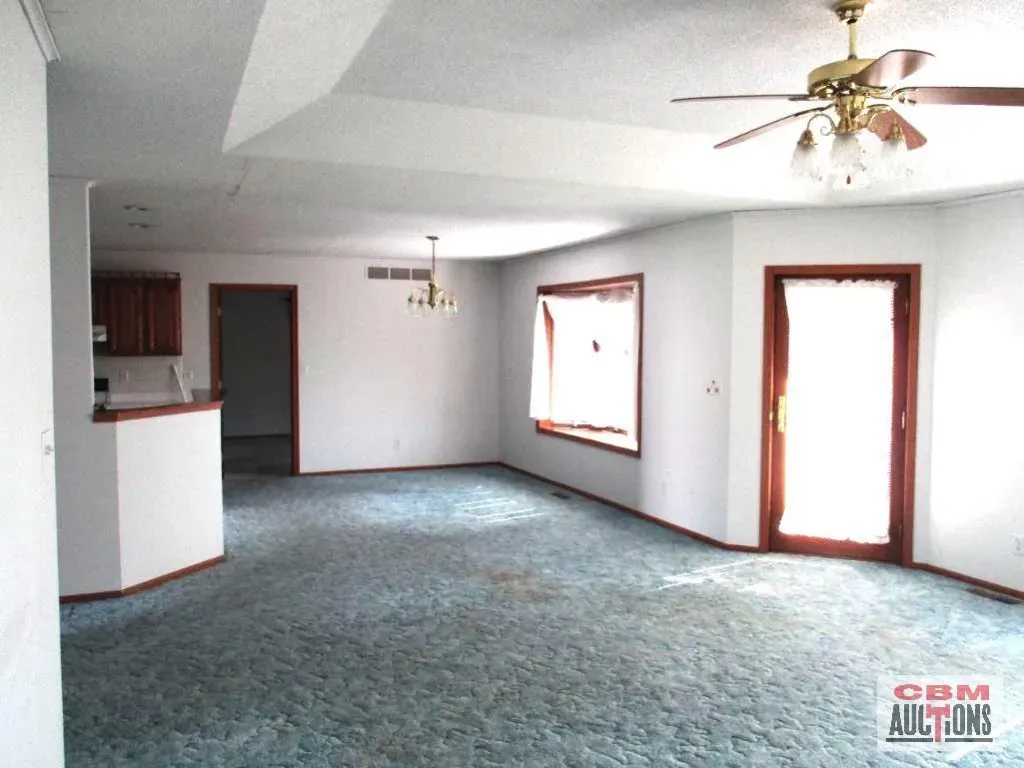 An empty living room with a ceiling fan and gdm auctions written on the wall
