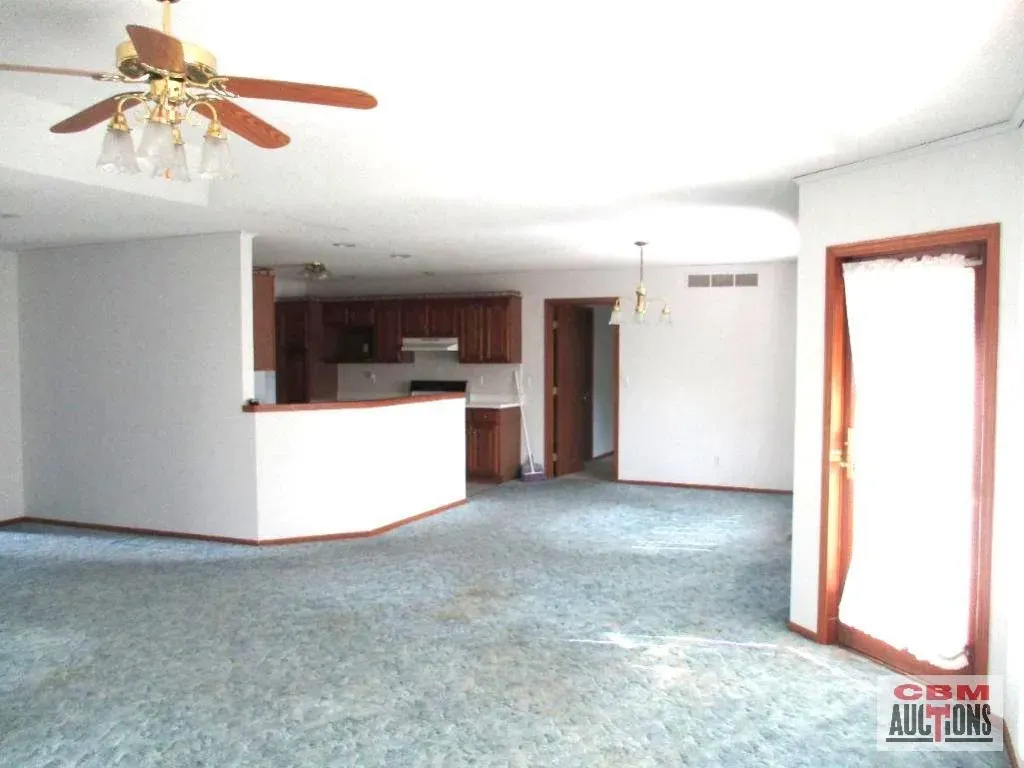 An empty room with a ceiling fan and a sign that says com auctions