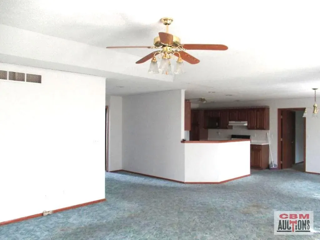 An empty room with a ceiling fan and a sign that says odm auctions
