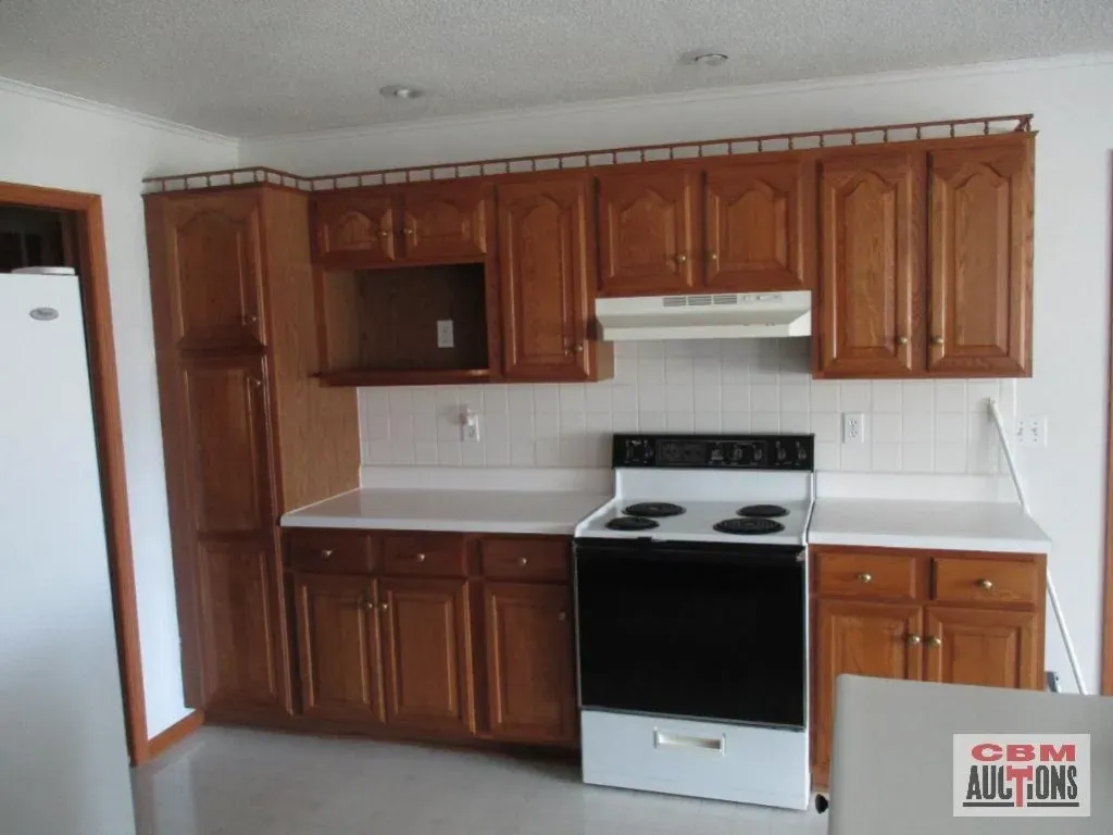 A kitchen with wooden cabinets and a stove that says com auctions