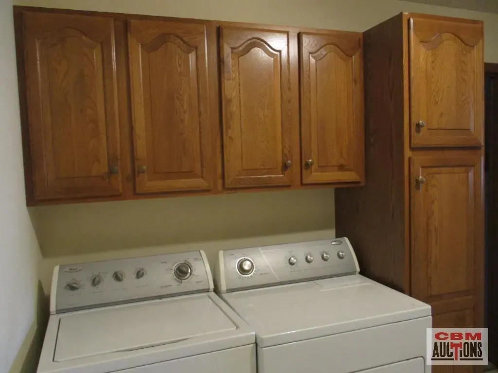 A laundry room with wooden cabinets and a washer and dryer