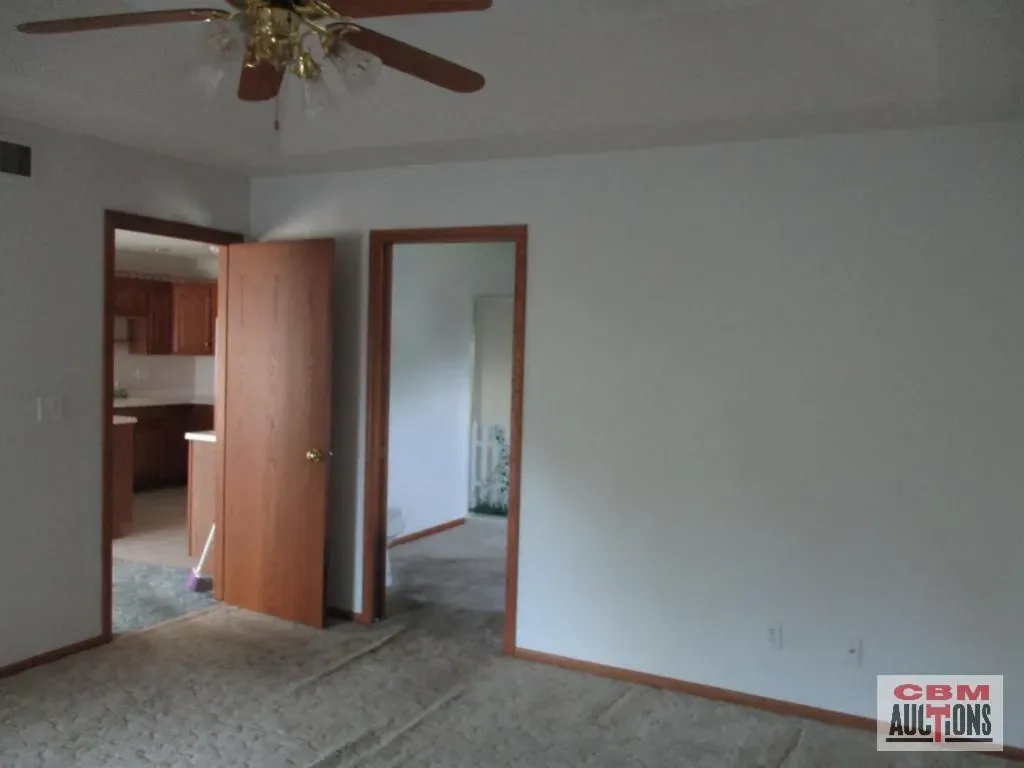 An empty room with a ceiling fan and a sign that says com auctions