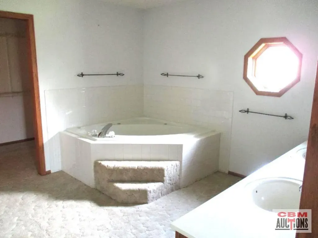 A bathroom with a jacuzzi tub and a sink and the words cdm auctions on the bottom