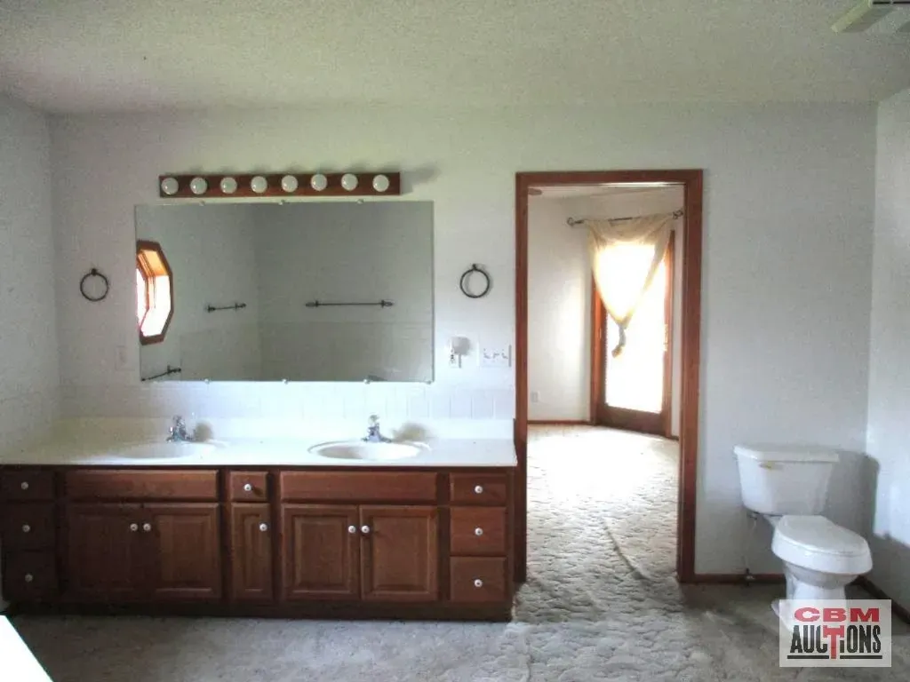 A bathroom with two sinks and a toilet and a sign that says com auctions