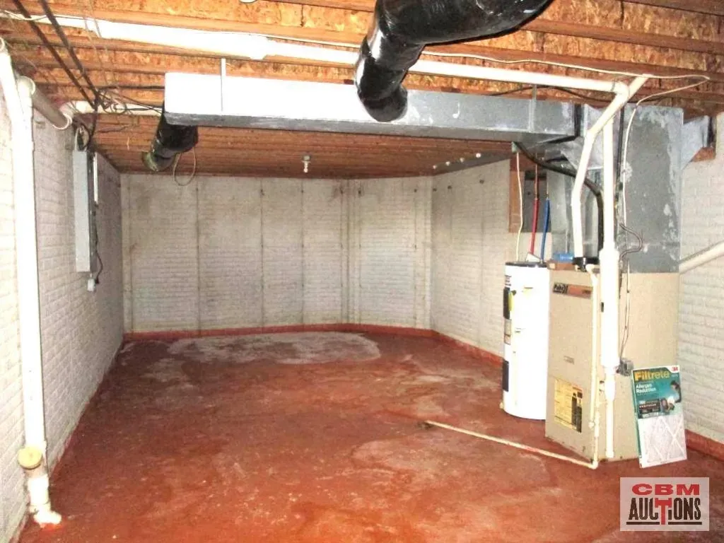An empty basement with a cbn auction sign on the wall