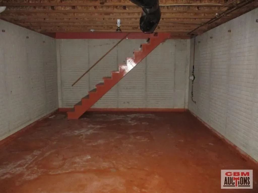 An empty room with a red staircase and a sign that says com auctions