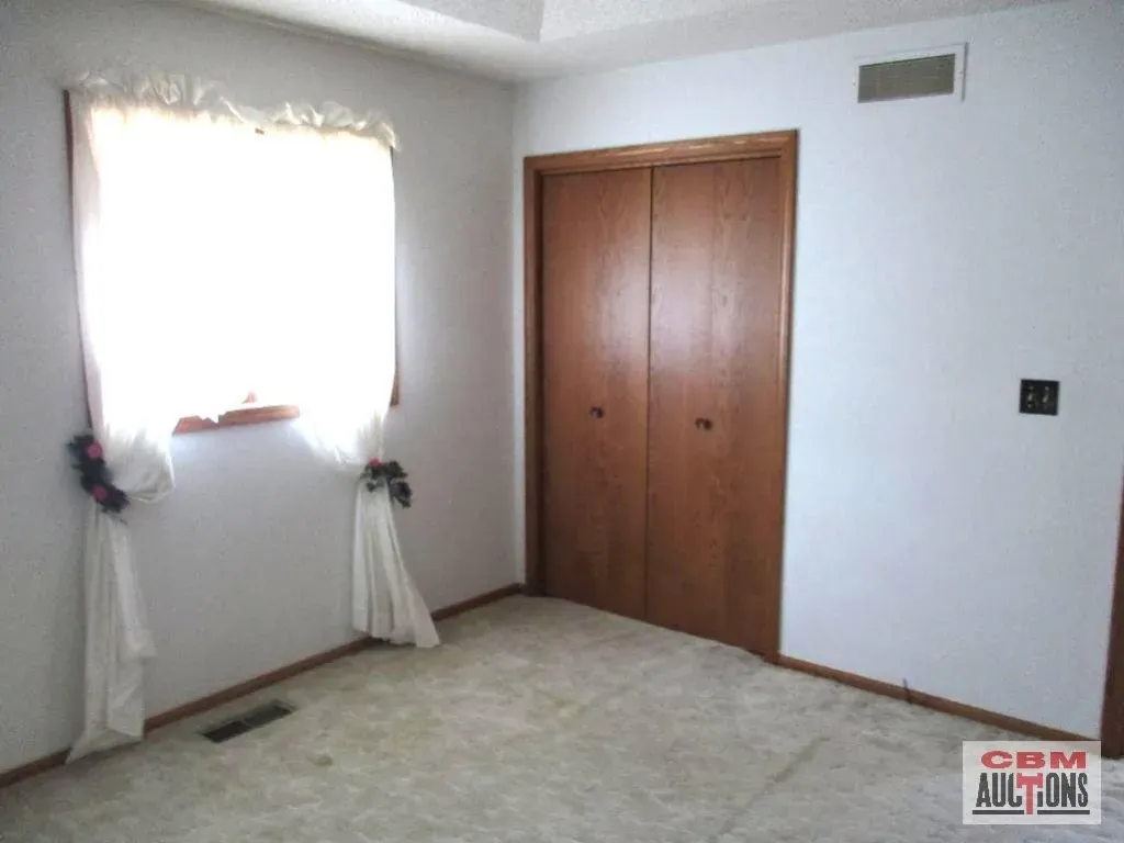 A room with a closet and a window with a sign that says com auctions