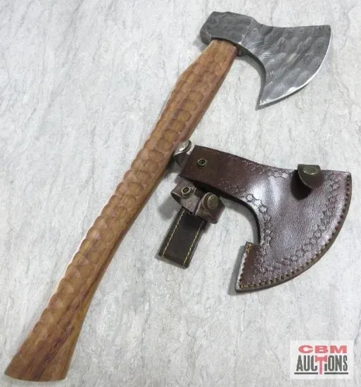 Hand axe with wooden handle and leather sheath on a textured surface.