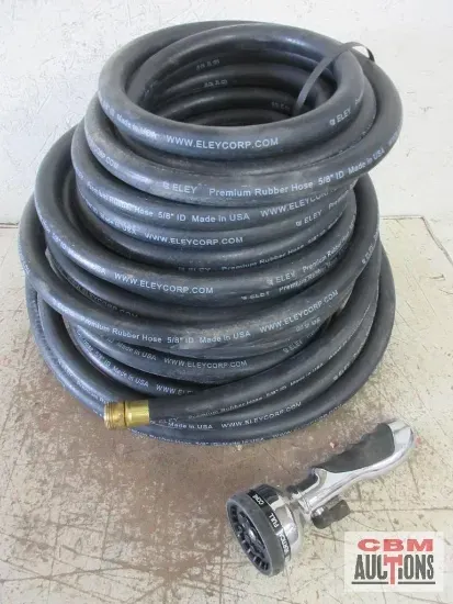 Coiled black garden hose with metal sprayer nozzle on a concrete surface.
