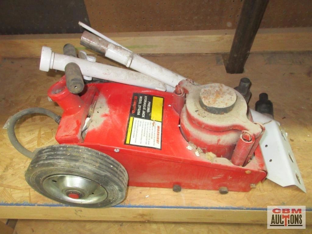 Hand axe with wooden handle and leather sheath on a textured surface.