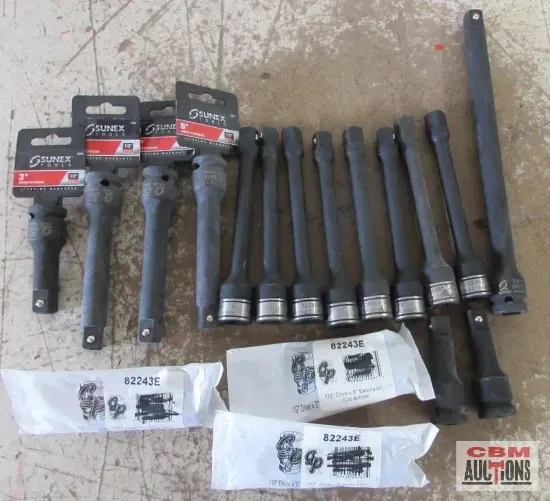 A set of automotive tools on a concrete surface. Includes socket extensions and a ratchet adapter.
