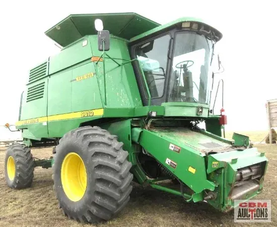 A green john deere combine harvester is parked in a field