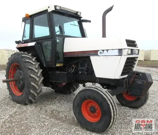 A white case tractor is parked in a gravel lot