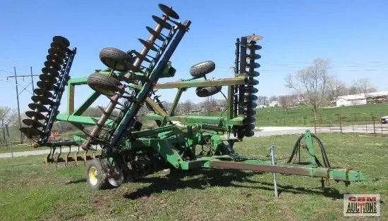 A green and black tractor is parked in a grassy field.