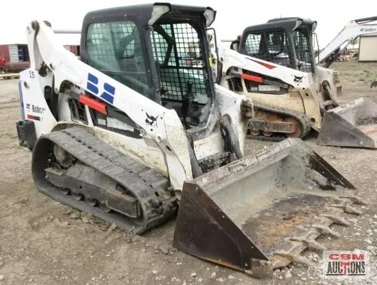 Two bobcat tractors are parked next to each other