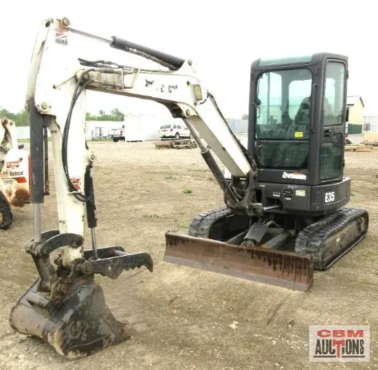 A bobcat excavator is sitting in a dirt field at a cbm auction