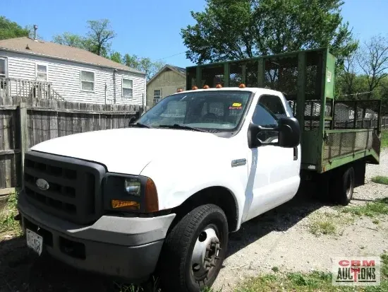 A white truck with a green bed is parked in front of a house