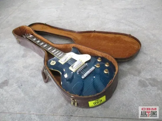A blue electric guitar is in a brown case