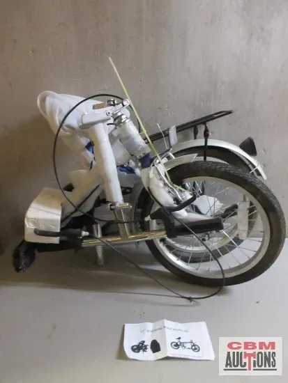 A folding bicycle is sitting on a table next to a manual.