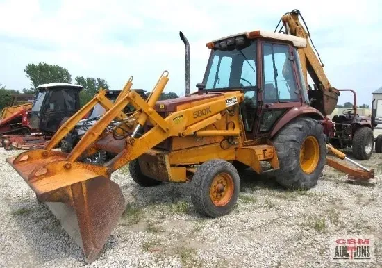 Yellow Case 580K backhoe on a gravel lot, with a front loader and backhoe arm extended.