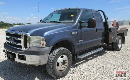 Blue Ford F-350 dually flatbed truck parked outdoors on a sunny day.