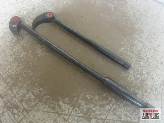 Two black tire tools with red caps lie on a speckled surface.