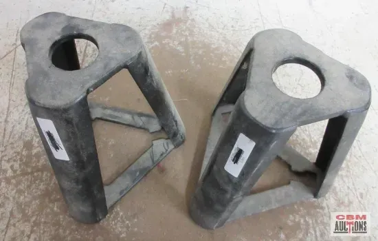 Two black triangular automotive jack stands with center holes, outdoors.
