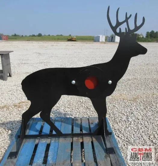 Black metal deer silhouette target with red bullseye, set on a wooden pallet outdoors.