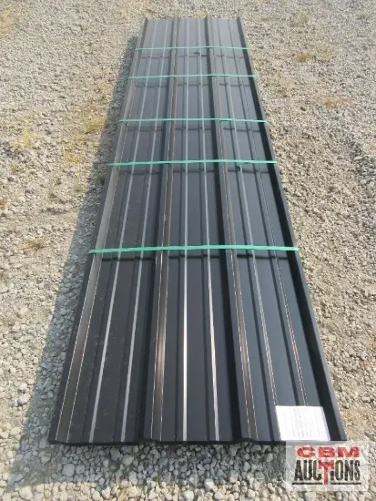 Black corrugated metal roofing bundle, secured with green straps, outdoors.