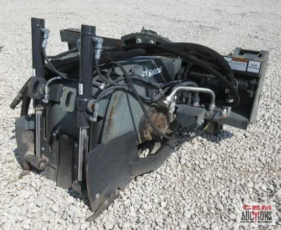 Gray brush cutter attachment on gravel, with black hoses and hydraulic cylinders.