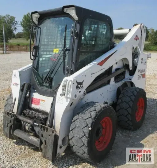 White Bobcat skid-steer loader with black cab and red wheel rims, in an outdoor setting.