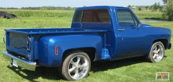 A blue truck is parked in a grassy field.
