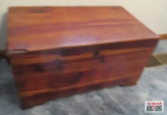 A wooden trunk is sitting on a rug with a gsm logo in the corner