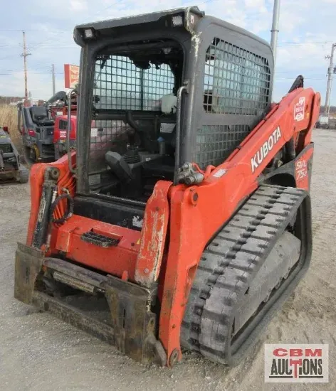 A kubota skid steer is parked in a dirt lot