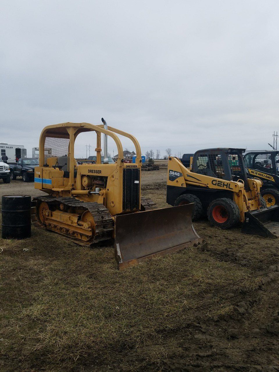 A bulldozer is parked next to a smaller bulldozer in a field.