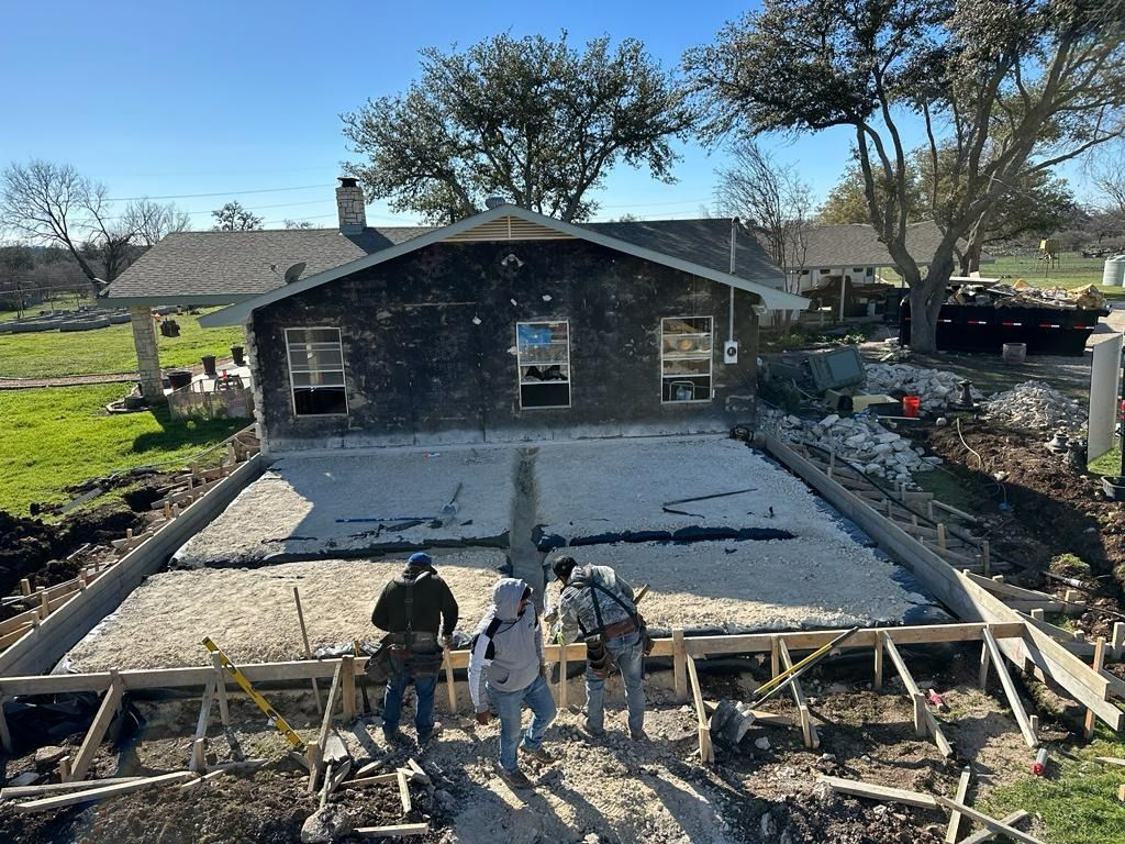 Construction workers on a concrete foundation, building an addition to a house.