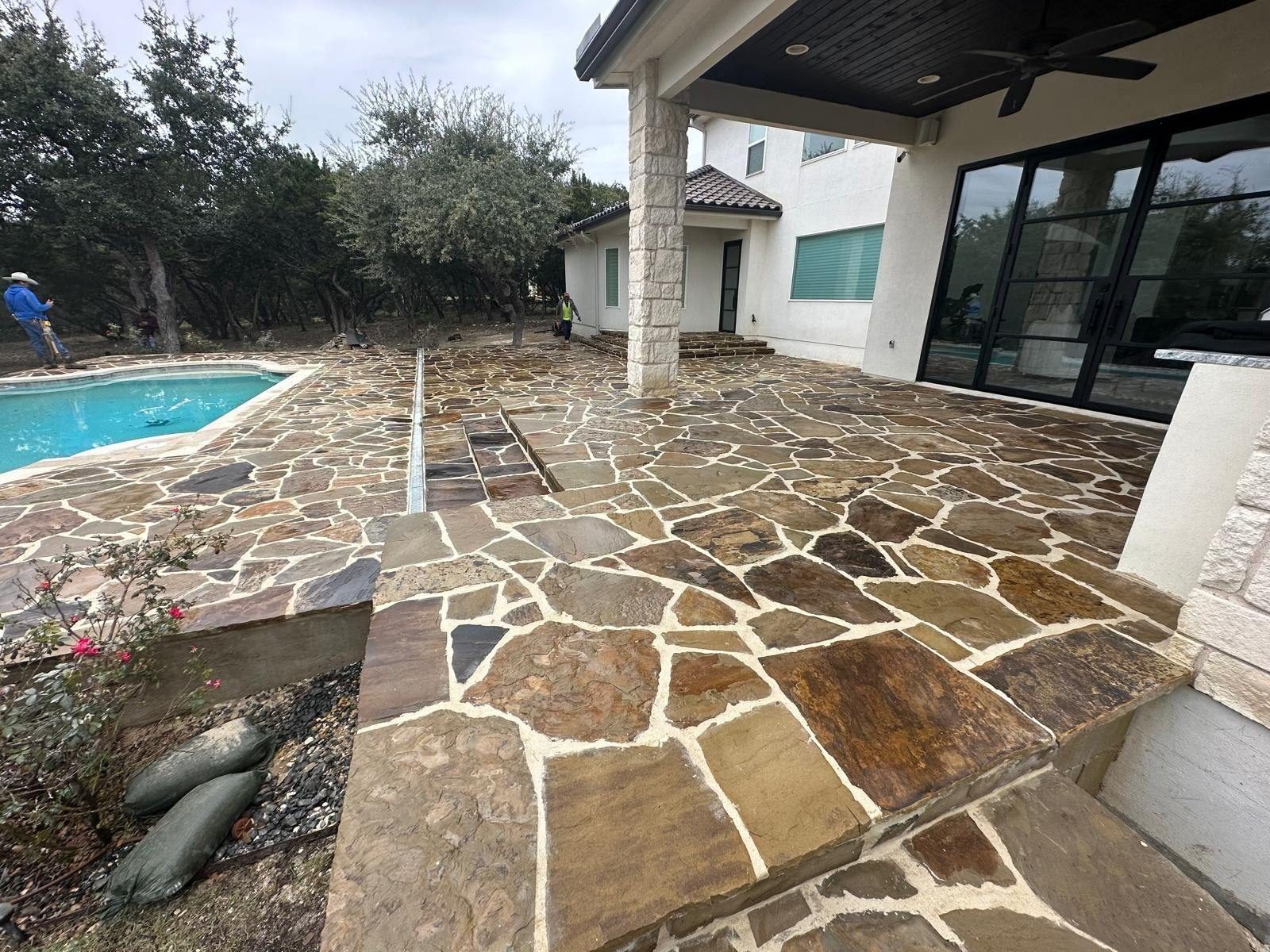 Patio with flagstone pavers, pool, and house exterior.