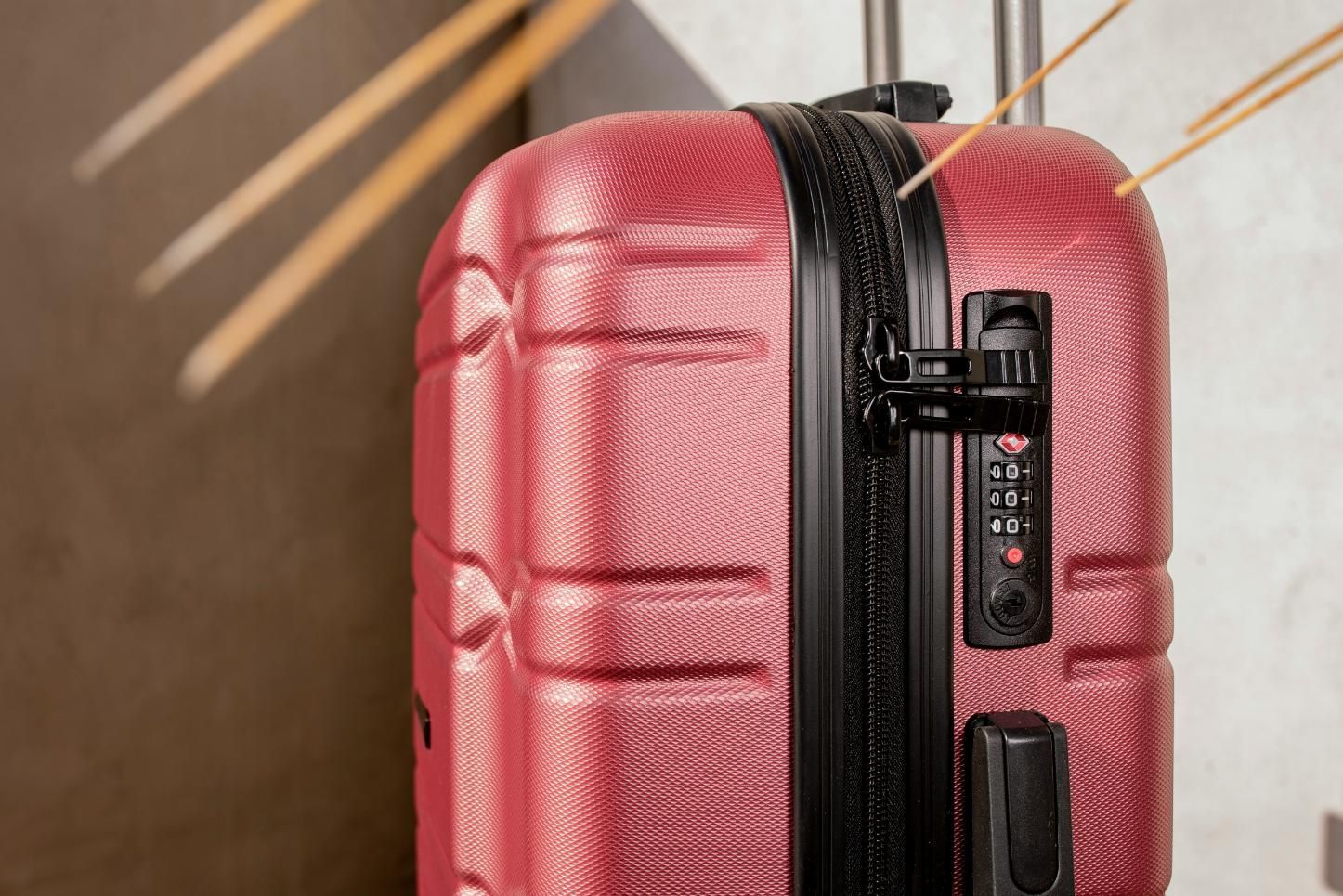 A close up of a red suitcase with a lock on it.
