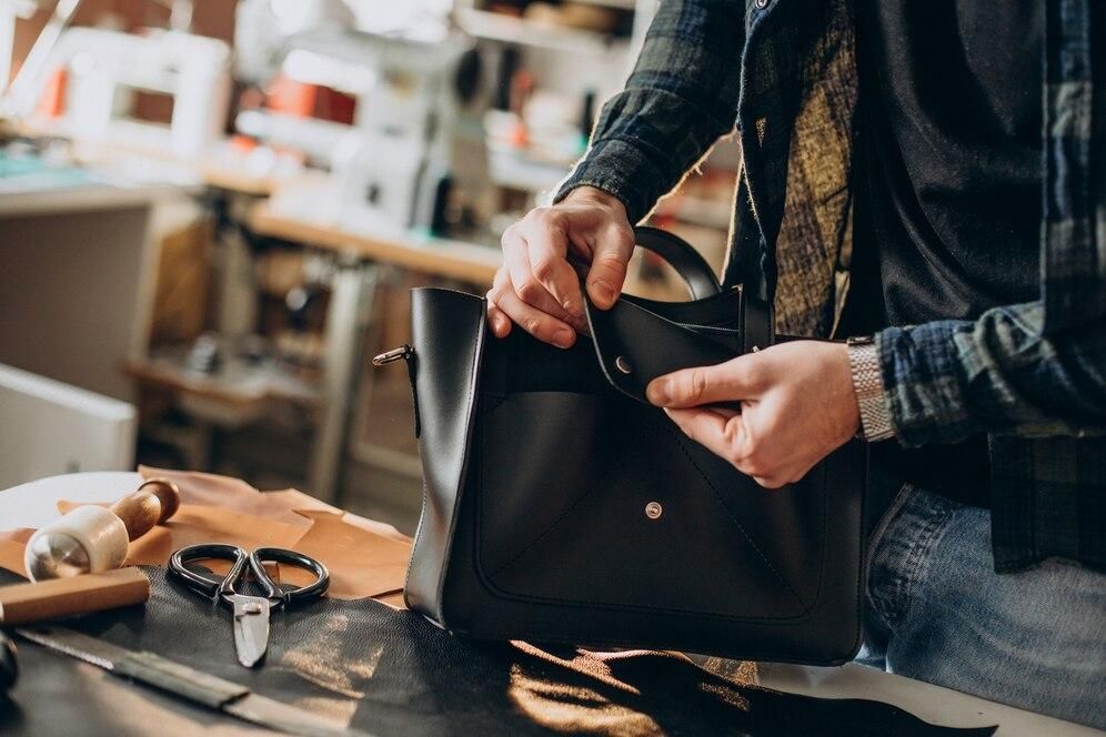 A man is making a leather bag in a workshop.