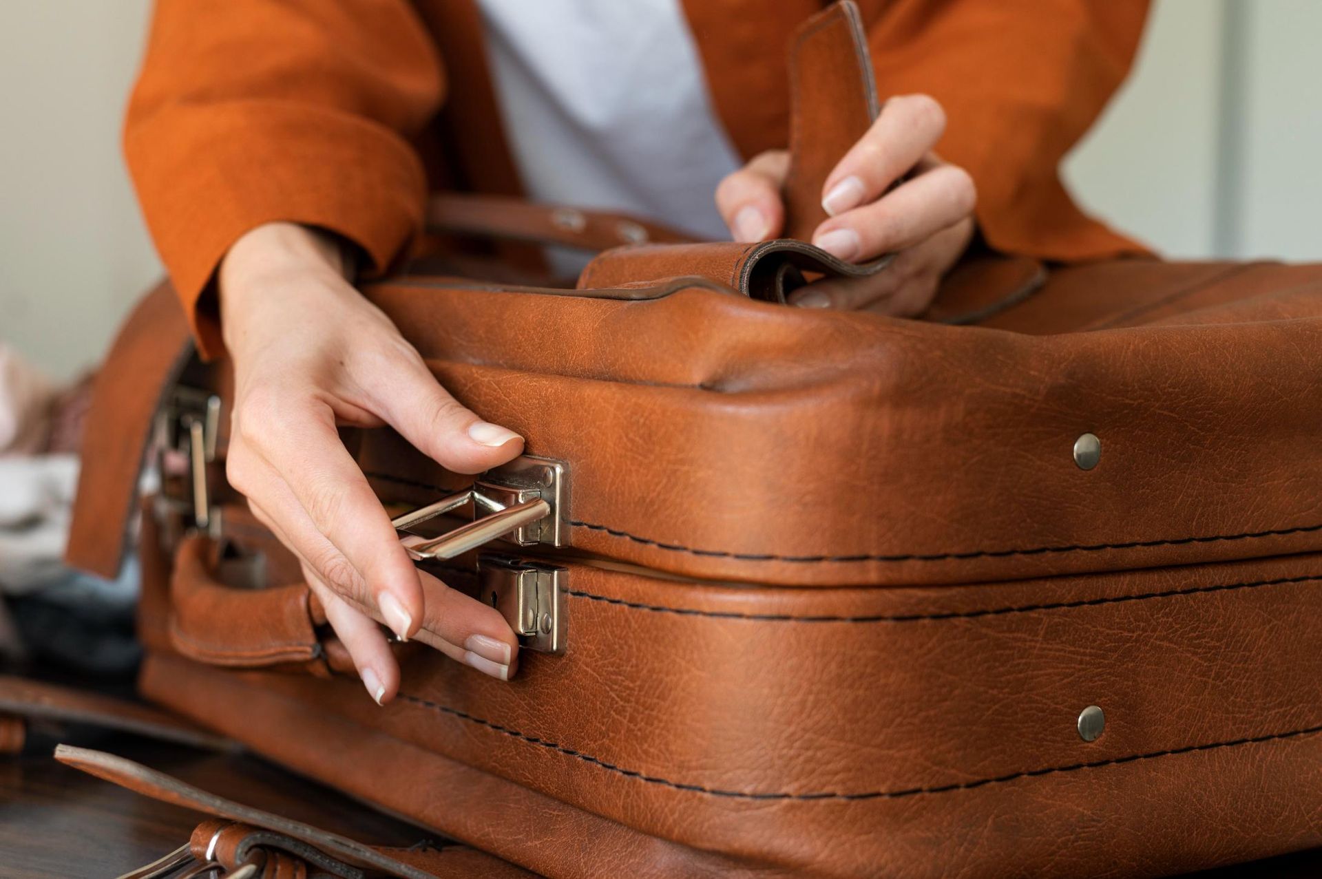 A woman is holding a brown leather briefcase in her hands.