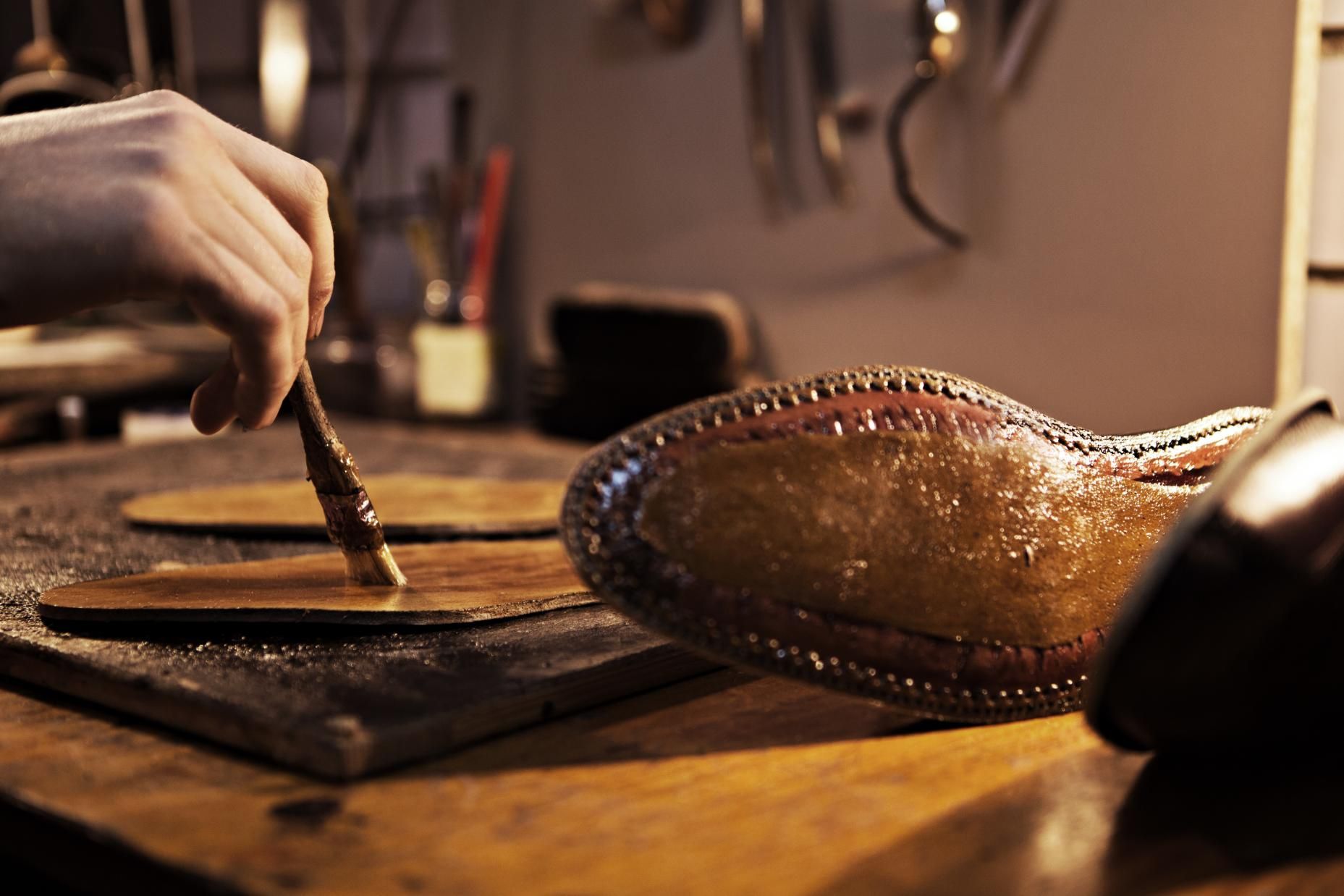 A person is painting a shoe with a brush.