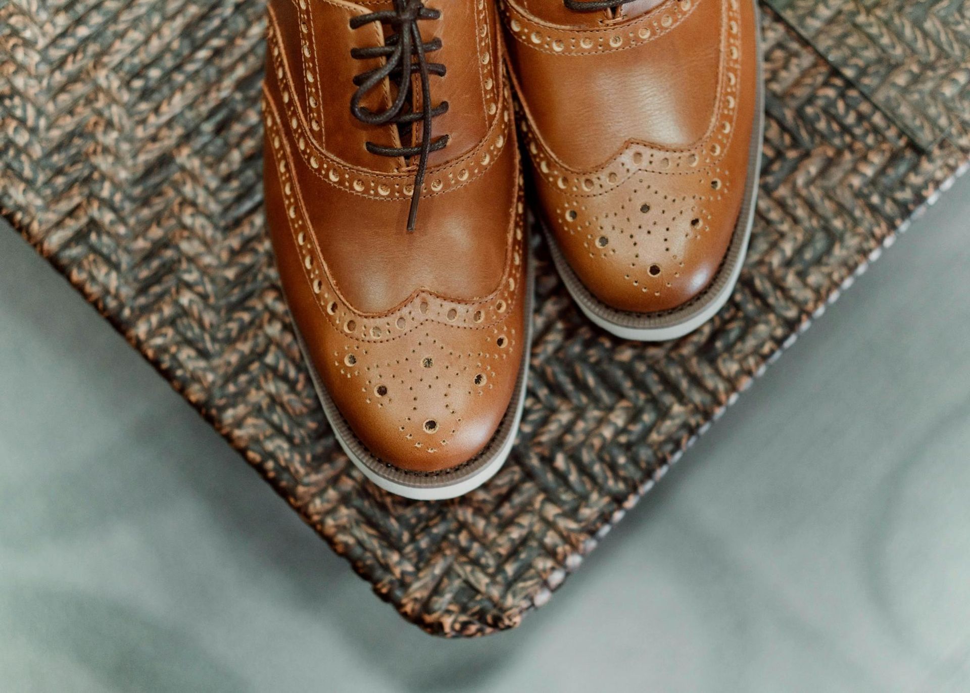 A pair of brown shoes are sitting on top of a rug.