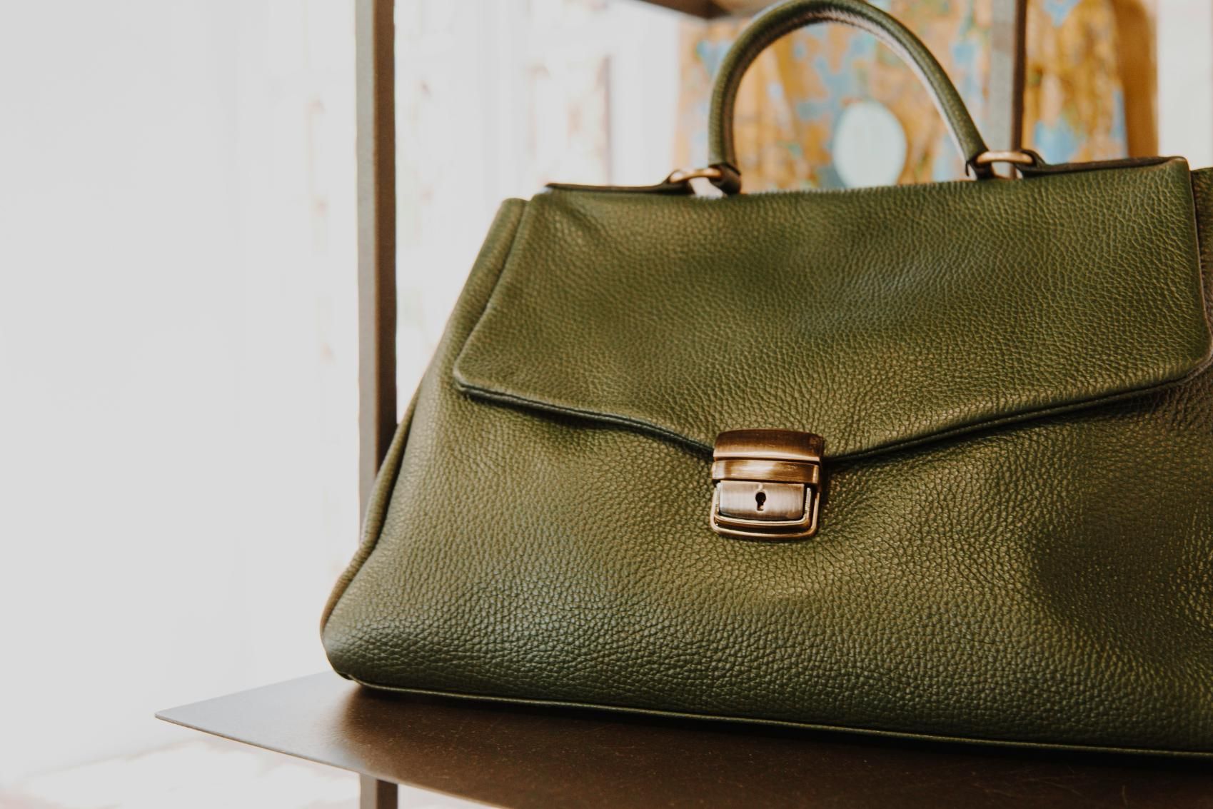 A green purse is sitting on top of a wooden table.